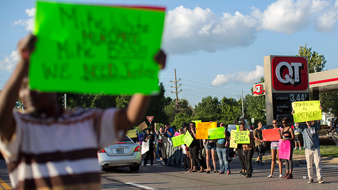 Demonstrators hold signs while protesting the death of black teenager Michael Brown in Ferguson, Missouri August 12, 2014 (Reuters / Mario Anzuoni)