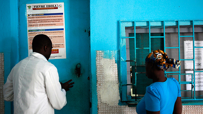 A woman stands at a pharmacy next to a poster displaying a government message against Ebola, at a maternity hospital in Abidjan August 14, 2014 (Reuters / Luc Gnago)
