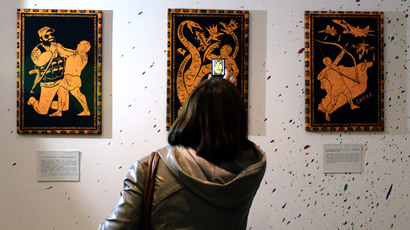 A visitor takes photos of the paintings during the "12 Labours of Putin" art exhibition on October 6, 2014  (AFP Photo / Vasily Maximov)