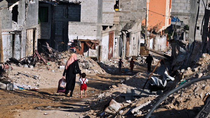 A Palestinian woman holds the hand of a child as they head home with some of their belongings on August 27, 2014 in Gaza City's Shejaiya neighbourhood which was one of the hardest hit by the fighting between Hamas militants and Israel.(AFP Photo / Roberto Schmidt)