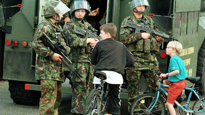 Young boys with their bikes chat to armed British soldiers on the Peace Line in West Belfast August 10, 1997 (Reuters)