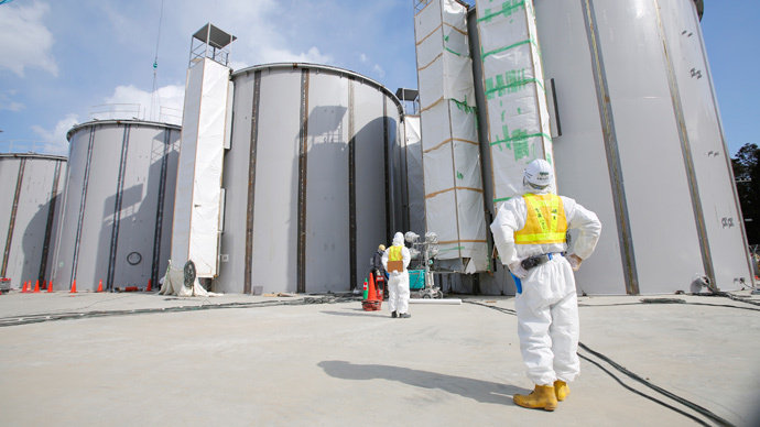 A worker, wearing a protective suit and a mask, looks up at welding storage tanks for radioactive water, under construction in the J1 area at the Tokyo Electric Power Co's (TEPCO) tsunami-crippled Fukushima Daiichi nuclear power plant in Fukushima prefecture (Reuters / Toru Hanai)