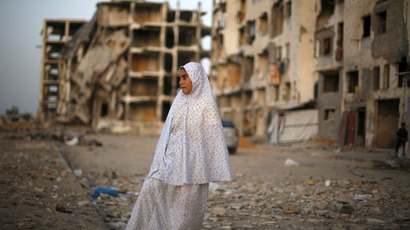 A Palestinian girl stands near residential buildings that witnesses said were heavily damaged by Israeli shelling during a 50-day war last summer, in Beit Lahiya town in the northern Gaza Strip May 25, 2015. (Reuters/Suhaib Salem)