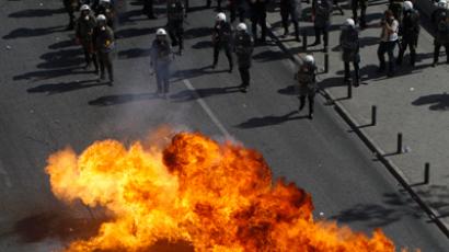 Flames from a molotov cocktail flare up near Greek riot police as they stand guard near a protest march by Greece's Communist party in central Athens during a 24-hour labour strike October 18, 2012 (Reuters / John Kolesidis)