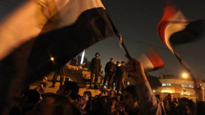 Egyptian army soldiers stand on top of a tank as opposition supporters and protesters wave national flags outside the presidential palace on December 9, 2012 in Cairo. (AFP Photo/Patrick Baz) 