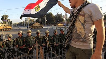 A protester against Egypt's President Mohamed Mursi waves an Egyptian flag in front of Republican Guard soldiers standing behind a barbed wire barricade guarding the presidential palace in Cairo. (Reuters / Mohamed Abd El Ghany)