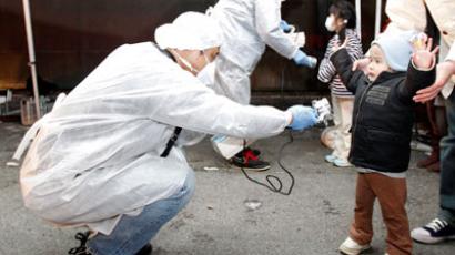 Officials in protective gear check for signs of radiation on children who are from the evacuation area near the Fukushima Daini nuclear plant in Koriyama, March 13, 2011.(Reuters / Kim Kyung-Hoon) 