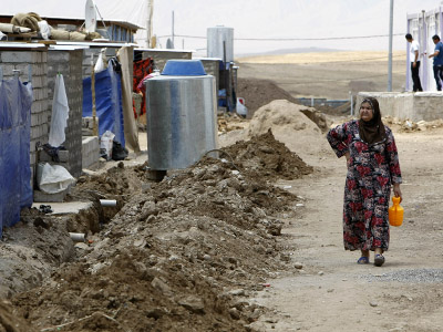 A Syrian-Kurdish refugee woman carries a container as she walk along a road in the Domiz refugee camp, 20 km southeast of Dohuk city, in northern Iraq, on July 17, 2012. (AFP Photo/Safin Hamed)