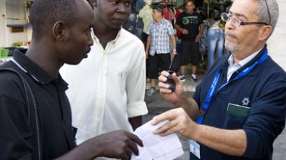 Israeli immigration officers check an African migrant in the Mediterranean city of Tel Aviv on June 12, 2012. (AFP Photo/Jack Guez)