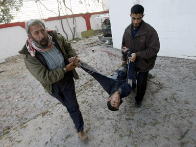 Palestinian men pull a man injured in the Zeitun district of Gaza City following Israeli strikes on January 12, 2009. (AFP Photo / Mahmud Hams)