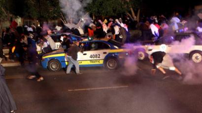 Kuwaiti opposition protestors take cover from tear gas fired by riot police during a demonstration demanding that the new parliament be dissolved and controversial legislation be scrapped in Kuwait City on January 6, 2013. (AFP Photo/Yaser Al-Zayyat)