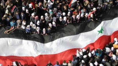Damascus: Syrians hold up a large national flags as they rally to show their support for their President Bashar al-Assad in the capital in Damascus. (AFP Photo/Louai Beshara)