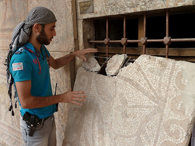 A Syrian rebel fighter inspects a mosaic piece at the Alma Arra museum in Maarat al-Numan, in Syria's northwestern Idlib province, on October 11, 2012. (AFP Photo / Herve Bar)