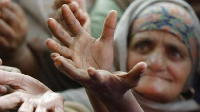 A Sikh devotee raises her hands to receive food from a roadside charitable community kitchen, on the outskirts of Jammu, India (Reuters / Mukesh Gupta)