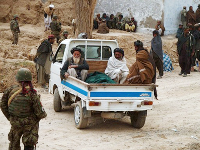 In a photograph taken on March 11, 2012, Afghan villagers sit in vehicles as they prepare to remove the victims of a shooting from homes in the village of Alkozai in Kandahar Province (AFP Photo / Jangir)