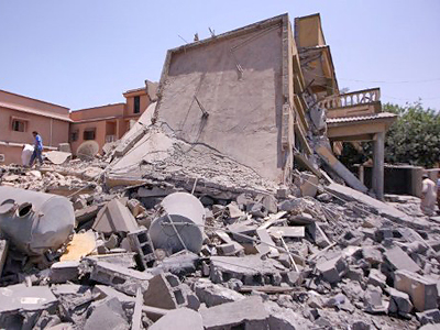 Locals inspect a damaged house in the Libyan coatal town of Zliten, 150 kilometres (95 miles) east of Tripoli, that a government official said was destroyed in a NATO aerial attack in which a mother and two children were killed on August 4, 2011.( AFP Photo / Imed Lamloum)
