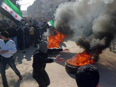 Syrian protesters burning tires and waving independence flags during an anti-regime demonstration on February 4, 2012 (AFP Photo / HO / LCC Syria)