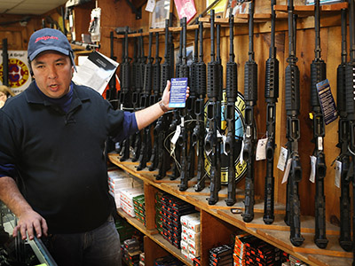 Jason Zielinski shows a customer a selection of AR-15 style rifles being offered for sale at Freddie Bear Sports sporting goods store on December 17, 2012 in Tinley Park, Illinois. (Scott Olson/Getty Images/AFP)