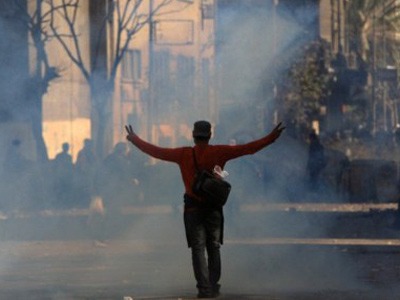 An Egyptian protester flashes the V for "victory" sign as he stands in a cloud of tear gas during clashes with riot police (AFP Photo / Mahmud Hams)