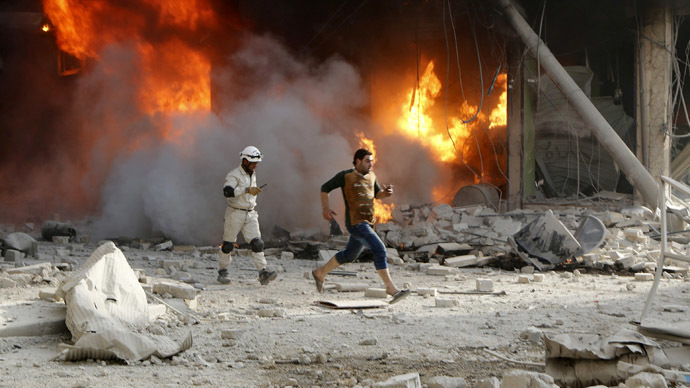 A member of the Civil Defence and a resident pass a fire at a site hit by what activists said were barrel bombs dropped by forces loyal to Syria's President Bashar al-Assad in Aleppo's al-Shaar district April 24, 2014. (Reuters/Hosam Katan)