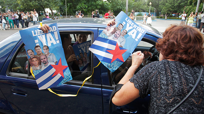 A woman celebrates with people riding in a car and holding posters of the "Cuban Five" in Havana December 17, 2014 (Reuters / Stringer)