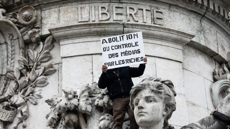 Un homme brandit une pancarte où est inscrit 